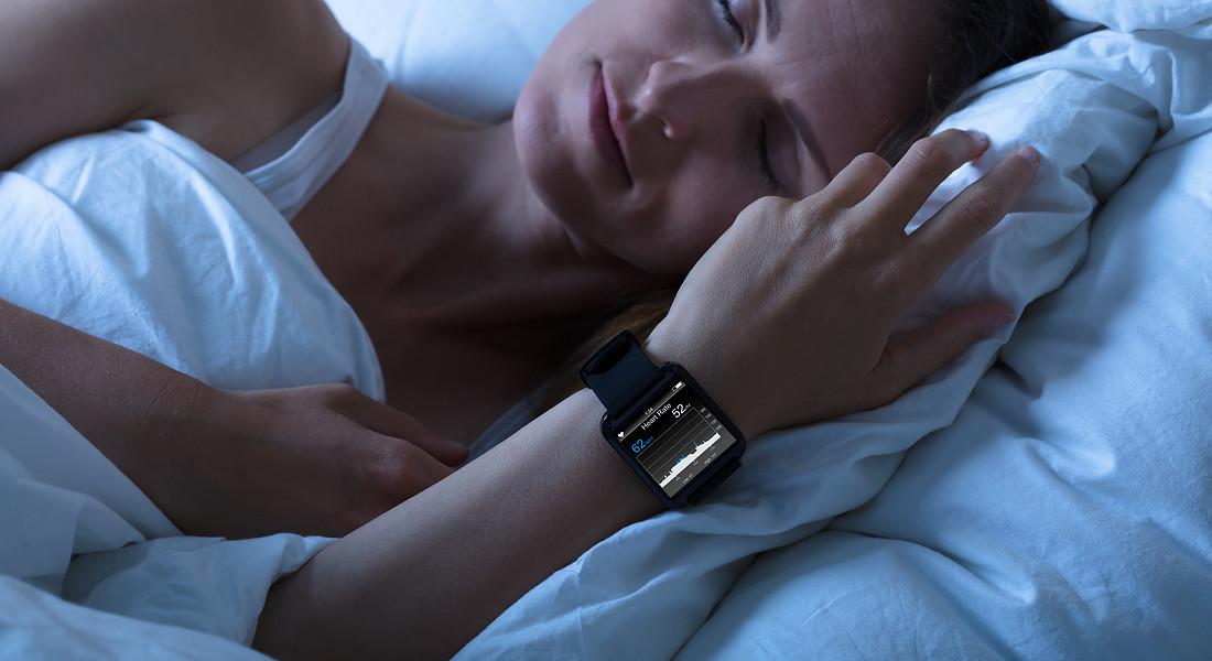 Una donna dorme con al polso uno sleep tool per monitorare il sonno foto iStock. © Ansa