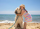 Una bambina abbraccia il suo cane in riva al mare foto iStock. (ANSA)