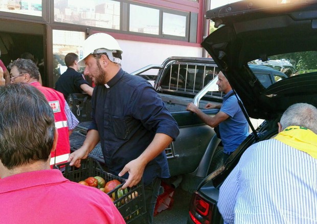 Don Fabio aiuta a scaricare i primi aiuti alimentari giunti dalla Coldiretti ad Amatrice © ANSA