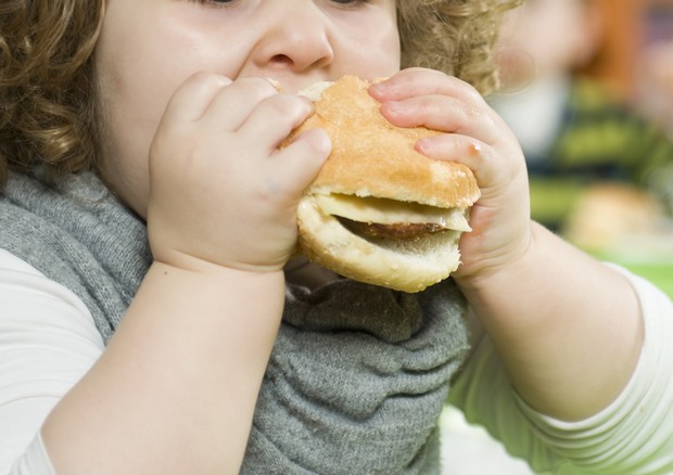Una bimba mangia un panino © Ansa