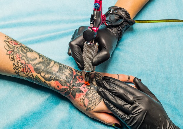 Una donna si fa fare un tatuaggio © Ansa