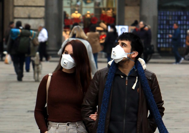 Una coppia di ragazzi passeggia per le vie del centro di Milano con il viso coperto da una mascherina © ANSA
