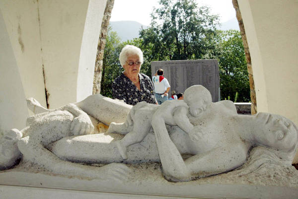 Una donna in preghiera al monumento che ricorda le vittime dell'eccidio di S.Anna di Stazzema