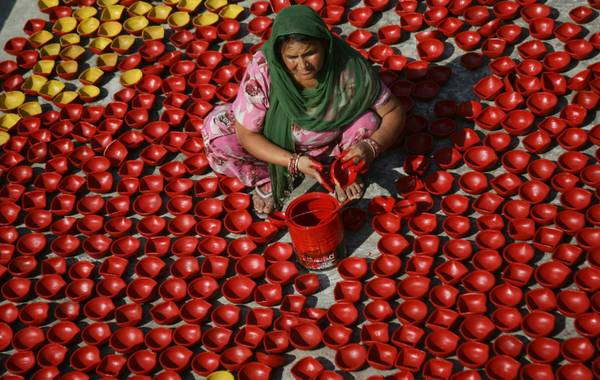 Una donna indiana dipinge di rosso le lanterne che saranno utilizzate per il Diwali Festival a Jammu, in Kasmir