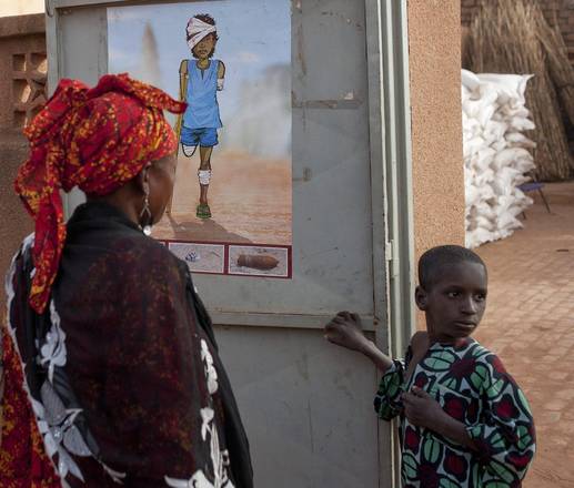 Abitanti di Konna, Mali, osservano un manifesto che avvisa, soprattutto i bambini, di stare lontani da granate o altre munizioni