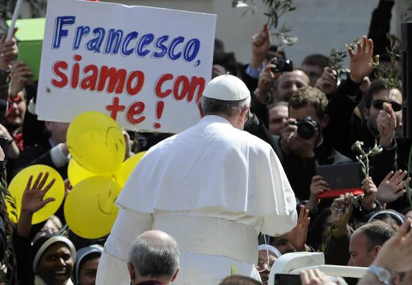 La folla saluta Papa Francesco, che in piazza muove sulla jeep, sventolando bandiere e soprattutto rami d'ulivo e foglie di palma