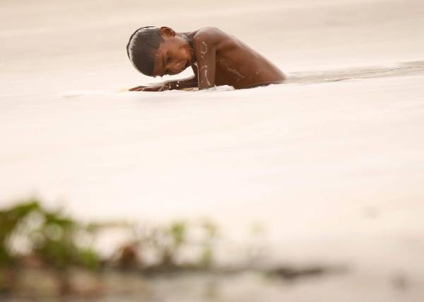 Un ragazzo indiano nuota nell'acqua  inquinata del fiume Yamuna a New Delhi