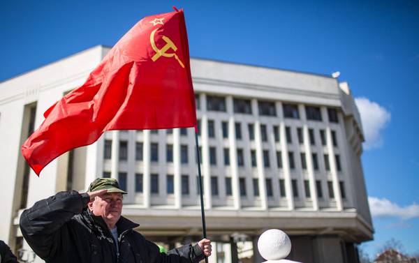 A man holding a Soviet era red flag salutes in front of the parliament building after the end of the referendum in Simferopol (Crimea).