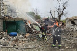 Firefighters fighting a blaze at a home after Russian strikes, in the town of Derhachi