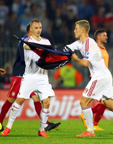 Due giocatori albanesi sistemano una bandiera del loro paese sul terreno di gioco prima di Serbia-Albania di qualificazione a Euro 2016 il 14 ottobre a Belgrado © EPA