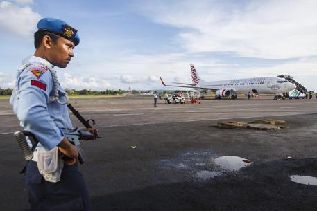 Un militare indonesiano vicino all'aereo della Virgin forzato ad atterrare a Bali © EPA