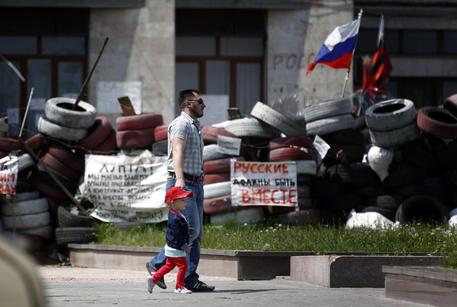 Un uomo e un bimbo passeggiano accanto alle barricate a Donetsk, Ucraina © EPA