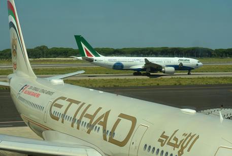 Un aereo della compagnia Etihad con uno dell'Alitalia sullo sfondo all'aeroporto di Fiumicino, 18 luglio 2014 © ANSA 