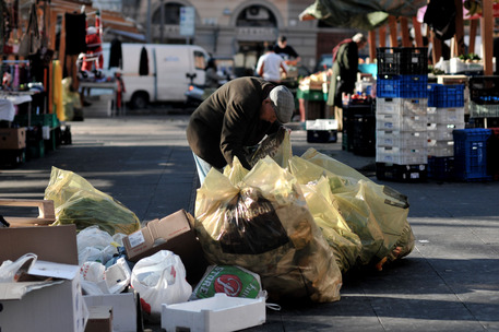 Un anziano fruga tra i rifiuti di un mercato © ANSA 