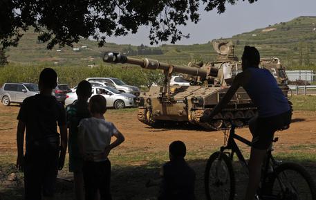 Alcuni ragazzi guardano l'artiglieria israeliana posizionarsi vicino al confine israelo-siriano sulle alture del Golan © ANSA 