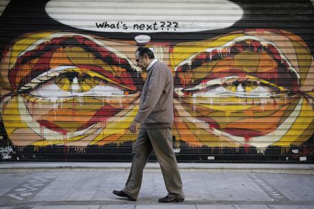 Un uomo passeggia per le vie di Atene (archivio) © AP