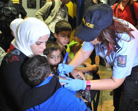 Polizia ceca marchia migranti con numeri sul braccio © AP