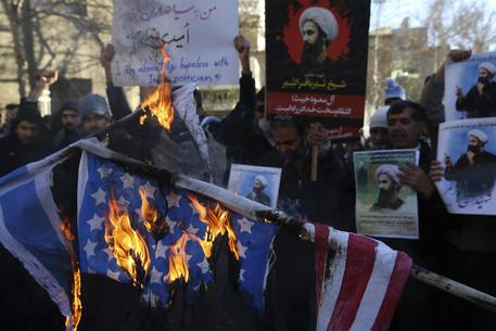 Una bandiera degli Stati Uniti data alle fiamme davanti all'ambasciata saudita a Teheran © AP