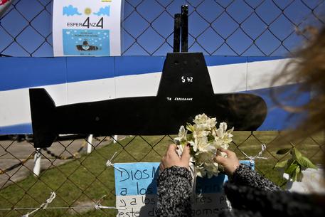 Una donna porta i fiori davanti ad un'immagine del sottomarino Ara San Juan sul recinto della base navale di Mar de Plata, in Argentina © ANSA