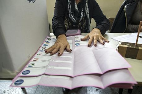 Una donna mostra la scheda elettorale per l'elezione del presidente del X municipio, in un seggio elettorale di Ostia, Roma, 5 novembre 2017 © ANSA