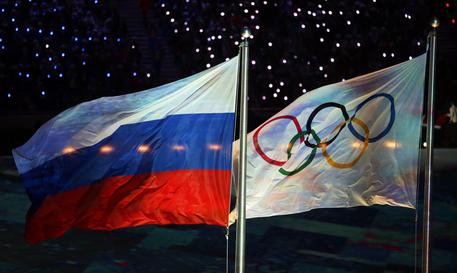 La bandiera olimpica e la bandiera russa durante la cerimonia di chiusura dei Giochi a Sochi nel 2014 © EPA