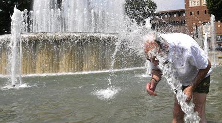 Un uomo si difende dalle alte temperature cercando refrigerio nella fontana di piazza del Castello © ANSA