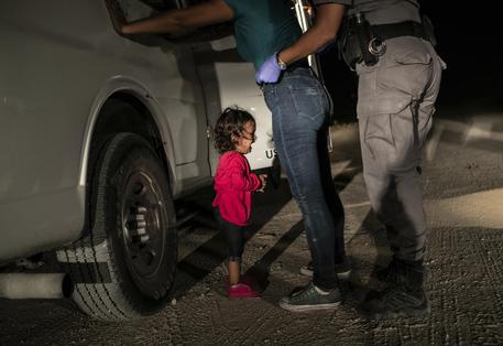 La foto di John Moore che ha vinto il World Press Photo of the Year: una bimba di 2 anni piange mentre la mamma richiedente asilo viene perquisita al confine USA-Messico a McAllen, Texas, il 12 giugno 2018 © AP