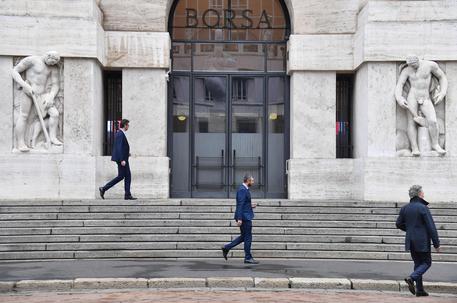 Alcune persone camminano davanti alla Borsa Italiana in piazza Affari, Milano © ANSA