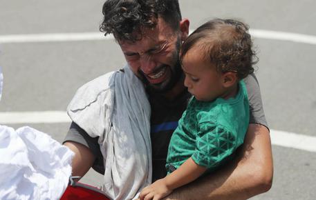 Un uomo prega di non essere preso dalle autorità stringendo il proprio bimbo durante un raid sulla carovana che dal Guatemala si stava dirigendo verso gli Usa © AP