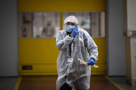 Dipendenti indossano mascherine e guanti protettivi a prevenzione della diffusione del Covid-19 in uno stabilimento industriale di packaging farmaceutico ad Aprilia, Roma © ANSA