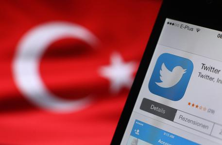 Il logo di twitter, sullo sfondo una bandiera turca © 