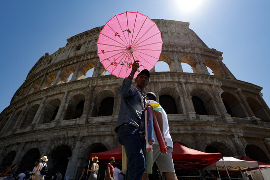 Vendedor se protege do calor no Coliseu de Roma, na Itália