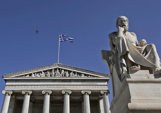 A Greek flag flutters at the Athens Academy © EPA
