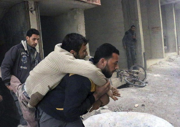 Un ferito viene soccorso da un membro del gruppo della Difesa Civile siriana dopo un attacco aereo © AP