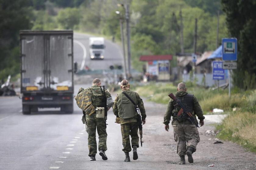 Pro-Russian militants walk as they guard a checkpoint in Semyonovka village, outside Slaviansk, Ukraine, 24 May 2014 © ANSA/EPA