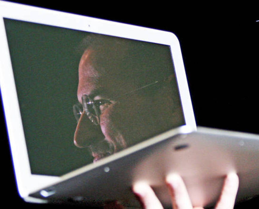 L'immagine di Steve Jobs riflessa sullo schermo di un portatile Apple © Ansa