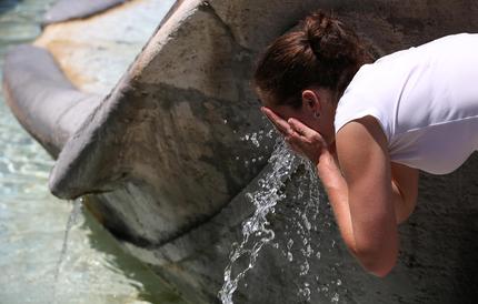 Una turista si rinfresca con l'acqua della fontana a Roma