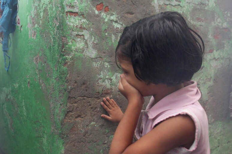 Una bambina si copre il volto con la mano in una foto d 'archivio - RIPRODUZIONE RISERVATA