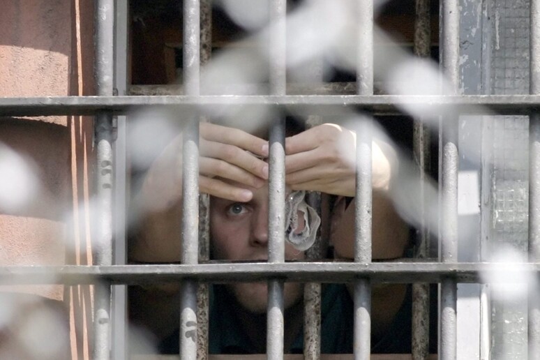 Un detenuto dietro le sbarre in una fotod 'archivio - RIPRODUZIONE RISERVATA