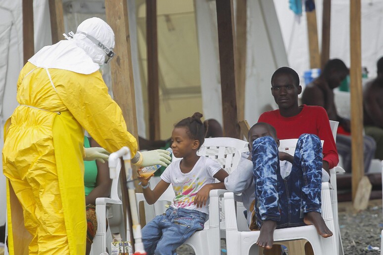 Un operatore mentre assiste una giovanissima contagiata di Ebola in Liberia © ANSA/EPA