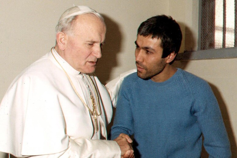 Giovanni Paolo II parla con il suo attentatore Mehmet Ali Agca nel carcere di Rebibbia in una foto del 1983 - RIPRODUZIONE RISERVATA