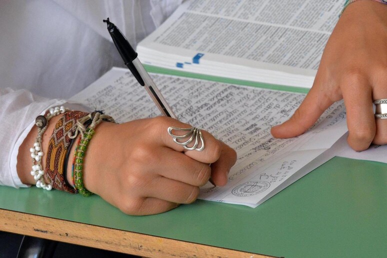 Una studentessa mentre scrive - RIPRODUZIONE RISERVATA