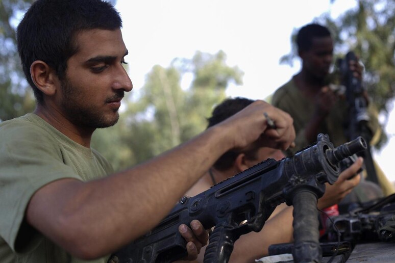 Un soldato israeliano ripulisce la propria arma © ANSA/EPA