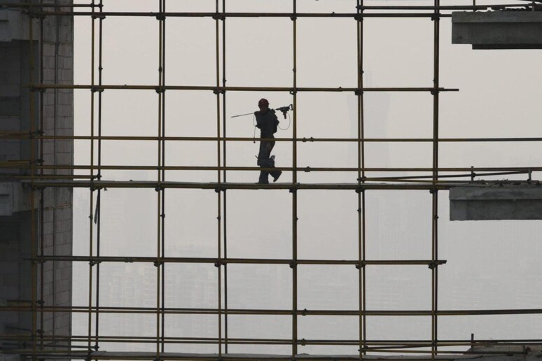 A worker walks on the scaffold between two building [ARCHIVE MATERIAL 20130307 ] - RIPRODUZIONE RISERVATA