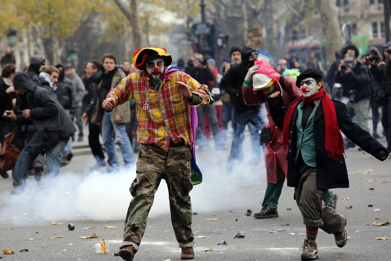 Attivisti scappano dopo gli scontri a Parigi per la conferenza sul clima © ANSA/AP