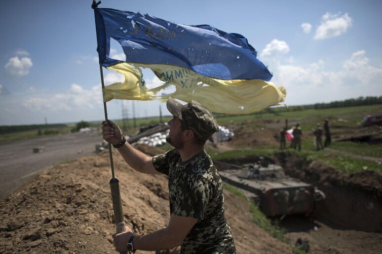 Un soldato con la bandiera ucraina a Marinka, vicino Donetsk, in una recente foto © ANSA/AP