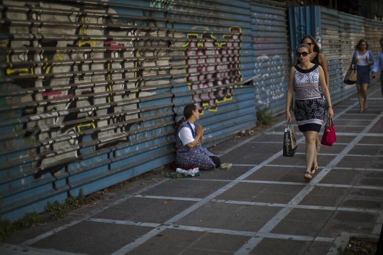 Una mendicante in una via di Atene © ANSA/AP