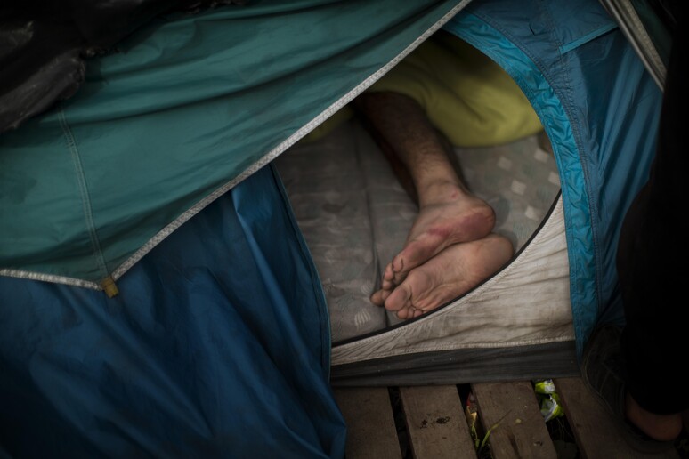 Un migrante dorme in una tenda a Calais © ANSA/AP