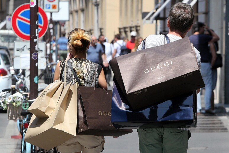 Una coppia a spasso per shopping in via Montenapoleone a Milano - RIPRODUZIONE RISERVATA