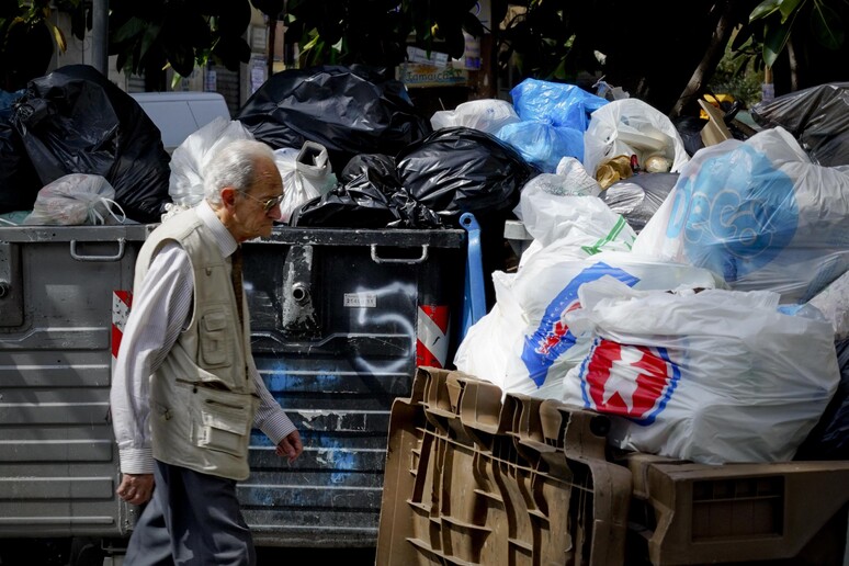 Un anziano davanti a un cassonetto di rifiuti - RIPRODUZIONE RISERVATA